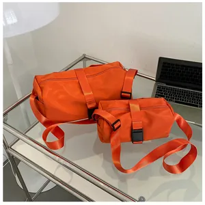 Dos vibrantes bolsas de deporte de nailon naranja de diferentes tamaños en mesa de cristal
