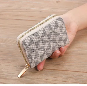 Hand holding a stylish geometric monogram card holder with premium gold zipper detail
