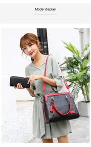 Modelo asiática luciendo un bolso negro grabado con detalles rojos y cartera a juego