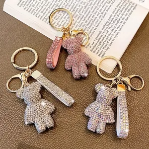 Detail of three rhinestone-encrusted bear keychains in pink, silver, and iridescent colors