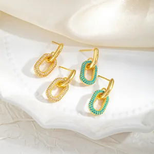 Gros plan de boucles d'oreilles géométriques plaquées or avec zircons et détails turquoise
