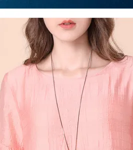 Detailed view of a minimalist silver long necklace worn on a textured pink blouse