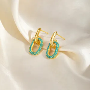 Gros plan de boucles d'oreilles double anneau géométriques plaquées or 16k avec zircons bleus.