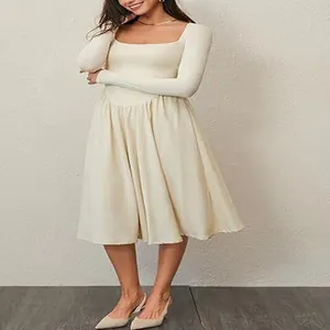 Detailed view of an elegant cream long-sleeved pleated dress with a square neckline