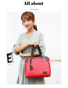 Elegante bolso de mano rojo y negro con letras grabadas, sostenido por una modelo.