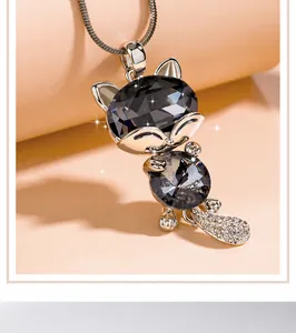 Macro view of an elegant cat pendant necklace with dark grey crystals on a warm beige background