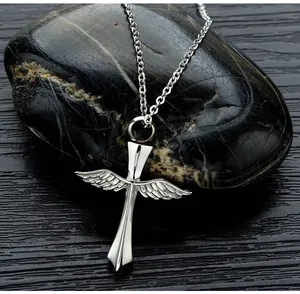 Detailed macro shot of a stainless steel winged cross urn necklace on dark stone background