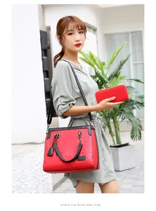 Modelo asiática con bolso de mano de cuero rojo grabado y cartera a juego en una escena callejera