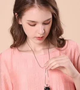 Detailed view of a long necklace with a black cat crystal pendant on a model.
