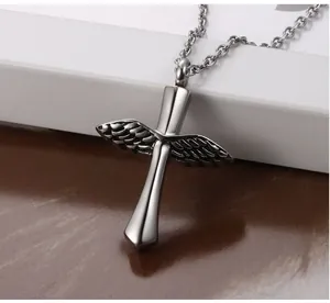 Close-up of a vintage stainless steel winged cross urn pendant with detailed metallic texture.
