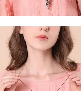 Close-up of elegant cat crystal pendant necklace on a pink textured blouse.