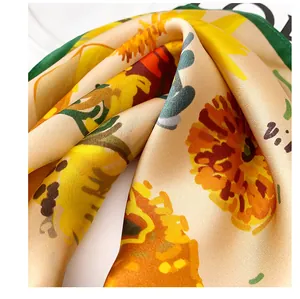 Close-up detail of luxurious silk square scarf with vibrant sunflower print pattern