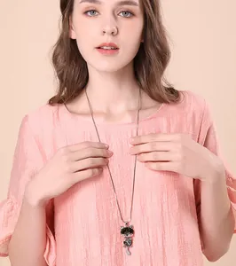A close-up detailed view of an elegant cat crystal pendant on a long sweater chain