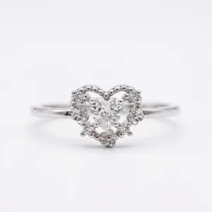 Close-up of a delicate heart-shaped ring featuring a center stone and floral pave details.