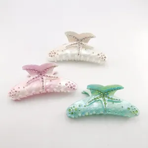Detail view of acetate starfish hair claw clips with rhinestones in three colors.