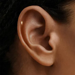 Close-up detail of a diamond-set gold rhombus cartilage stud earring worn on the ear helix