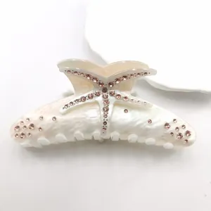 Detailed macro shot of marble acetate hair claw clip with pink rhinestone starfish.