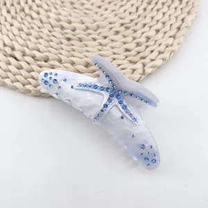 Detail of a white marble acetate hair claw clip with blue rhinestone starfish