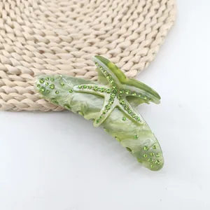 Detailed view of a green marble acetate hair claw clip with a rhinestone starfish motif.