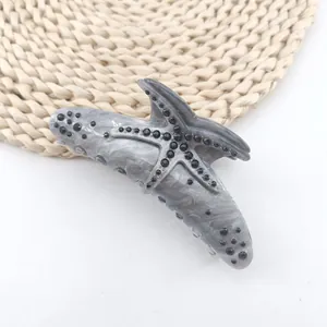 Detailed macro view of starfish hair claw clip with marble texture and black rhinestones