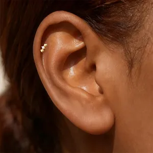 Detailed close-up of a gold heart-shaped zircon ear stud on a model's helix.