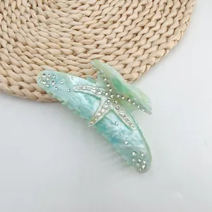 Macro view of a starfish hair claw clip with marble texture and sparkly rhinestones.