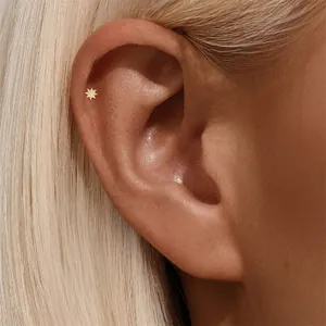 Close-up of gold eight-pointed star stud earring with crystals on ear bone.
