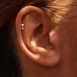 Close-up of elegant gold heart-shaped diamond stud earring worn on ear helix detail