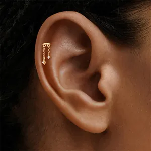 Detail shot of a gold S925 silver star tassel cartilage stud piercing on a human ear