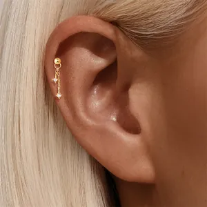 Detailed close-up of a gold star tassel cartilage stud worn on a helix piercing.
