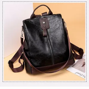 Close-up of black and brown PU leather anti-theft backpack with vertical zipper detail.