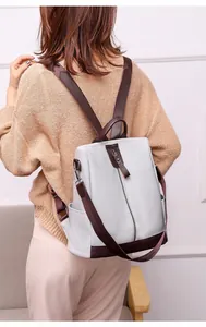 Detail shot of the back of a light gray PU leather anti-theft backpack on a model