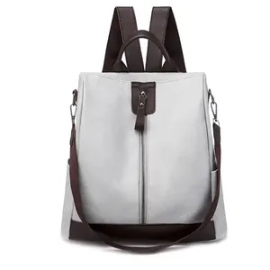 Elegant front view of a multifunctional grey PU leather backpack with brown strap accents.