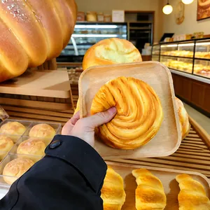 A hand squeezing a realistic croissant squishy toy to show its slow rise texture.