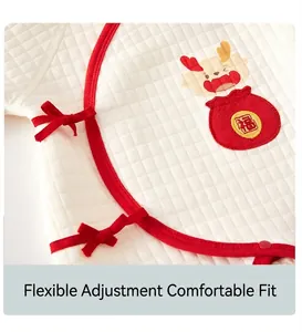 Gros plan d'un body matelassé pour nouveau-né avec des liens en ruban rouge et broderie