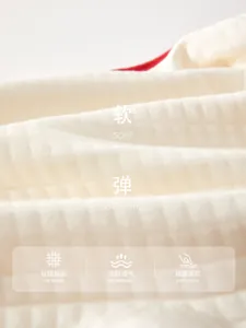 Gros plan sur un tissu texturé crème doux et extensible pour barboteuses pour nouveau-nés