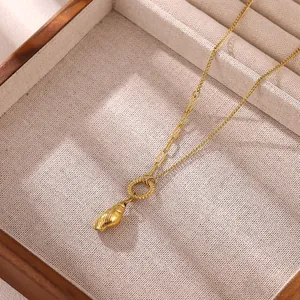 Dettaglio di una collana con ciondolo a conchiglia in oro in una scatola di legno portaoggetti.