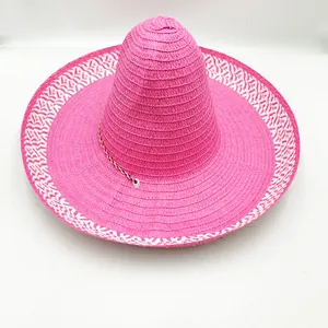 Vue détaillée d'un sombrero mexicain en paille rose vif à large bord décoré