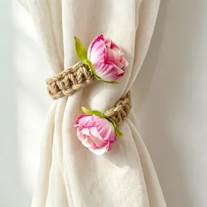Detail showing a pair of handmade bohemian jute rope curtain tiebacks with pink roses.