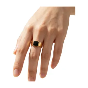 Simple gold titanium steel ring with a square black stone worn on a hand model.