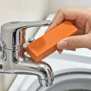 Close-up detail of an orange limescale eraser cleaning a shiny chrome faucet handle
