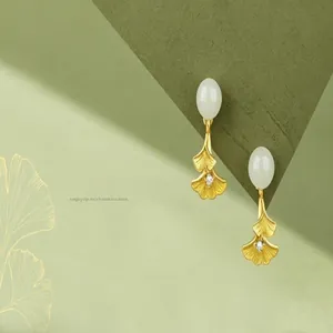 Detailed view of elegant gold ginkgo leaf drop earrings with white stones and crystals.