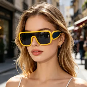 Primo piano di una modella con occhiali da sole gialli oversize in un contesto urbano