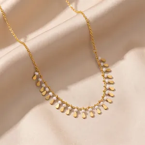 Close-up detail of a gold tassel clavicle necklace with teardrop charms and white beads
