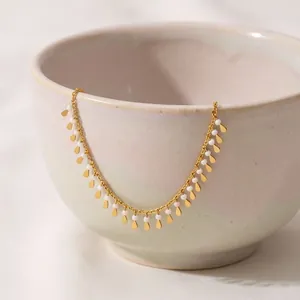 Close-up of gold tassel necklace with white beads draped on a ceramic bowl