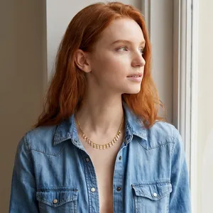 Detail shot of a golden choker necklace featuring delicate oval fringe tassels on a model.