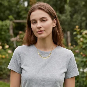Chic gold-toned collarbone necklace with oval tassel pendants on a grey t-shirt.