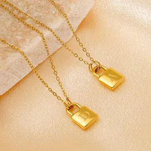 Detailed view of two 18K gold plated stainless steel necklaces with lettered lock pendants.