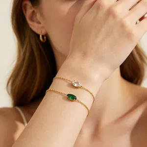 Detailed close-up of 18K gold plated stainless steel bracelet with green oval gemstones