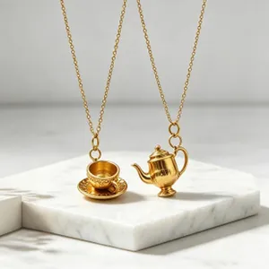 Detailed close-up of gold teapot and teacup pendants on a white marble display stand.